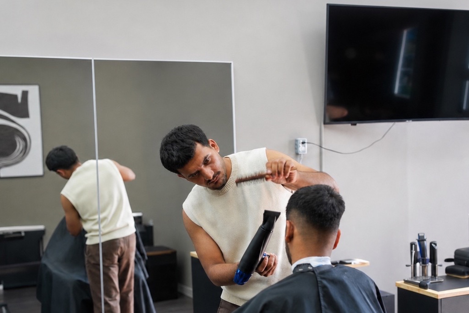 Muhammed shaping a client's haircut inside Barberhood York U